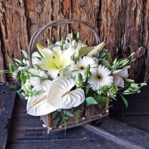 An overflowing floral flower basket in seasonal white flowers.
